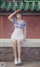 A woman sitting on a wall holding an orange.