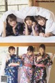 A group of women in kimonos laying on top of a bed.