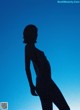 A silhouette of a woman standing in front of a blue sky.