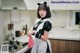 A woman in a maid outfit standing in a kitchen.