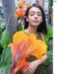 A young woman standing next to a large orange flower.