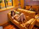 A woman sitting on a yellow couch in a living room.