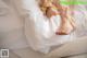 A woman's bare feet on a bed with white sheets.