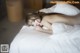 A naked woman laying on a bed with white sheets.